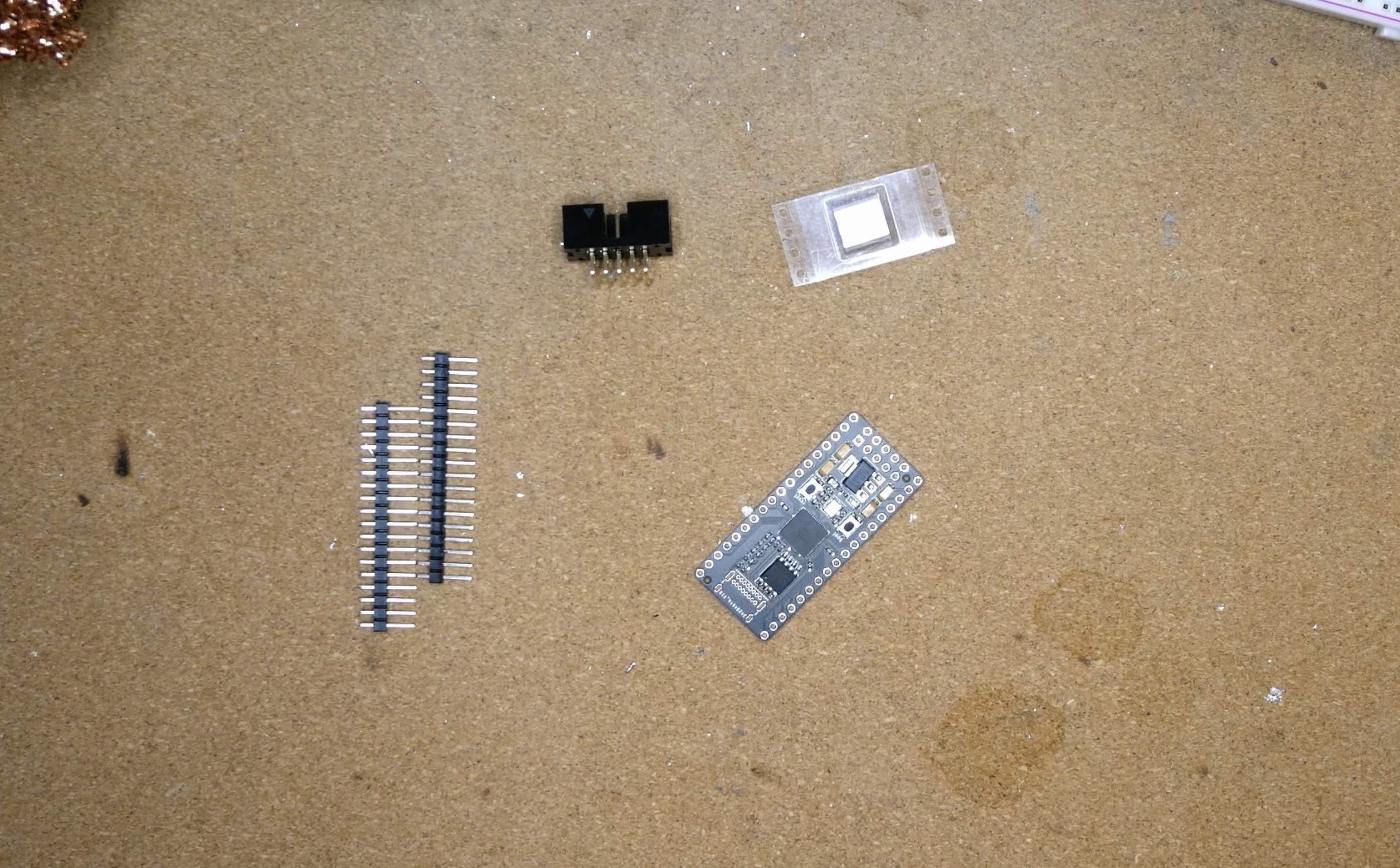 photo of a Chordata PCB, a USB Type-C port, 2 18-pin headers and a 2x5-pin shrouded right-angle header, on a cork desk mat